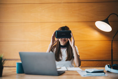 Woman wearing virtual reality headset while sitting at table