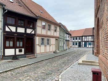 Houses by street amidst buildings against sky