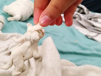 Cropped hand holding clay statue