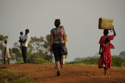 Rear view of people on field against clear sky