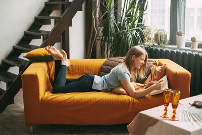 A young woman is lying on the sofa and reading a favorite book. the girl is resting, 