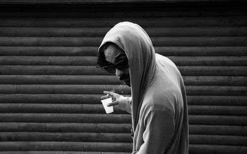 Man smoking cigarette while holding disposable cup