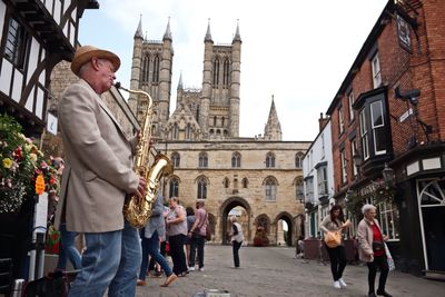 Man standing in town square against sky in city