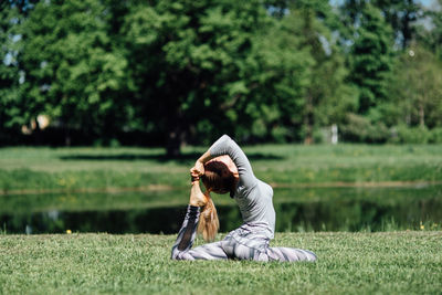 Young woman exercising by pond on field