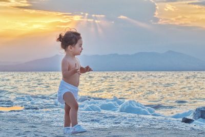 Full length of boy on beach against sky during sunset