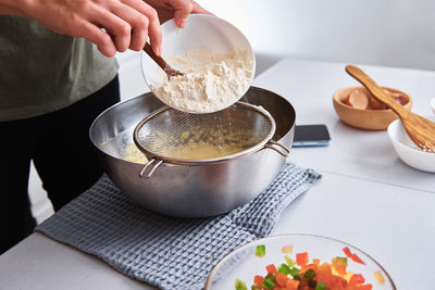 Woman in the kitchen cooking a dough. hands pour flour into a bowl