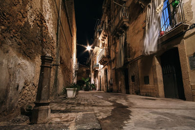 Narrow alley amidst buildings in city at night