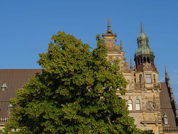 Low angle view of trees and building against sky