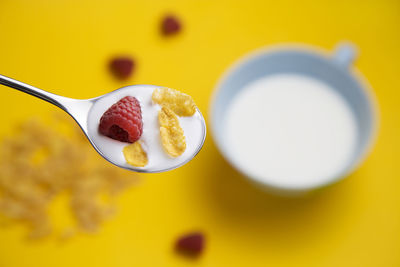 Close-up of breakfast cereal with raspberry and milk in spoon