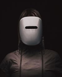 Close-up of woman wearing mask and hooded jacket against black background