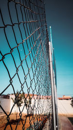 Close-up of chainlink fence against blue sky