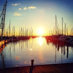 Sailboats moored on lake against sky during sunset