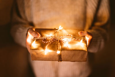 Close-up of person holding illuminated christmas gift