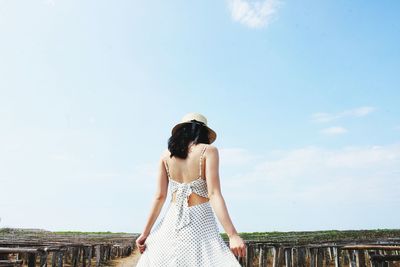 Rear view of young woman standing against sky