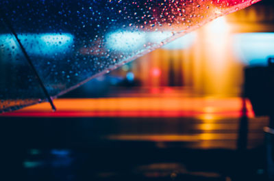 Cropped image of wet umbrella in city at night