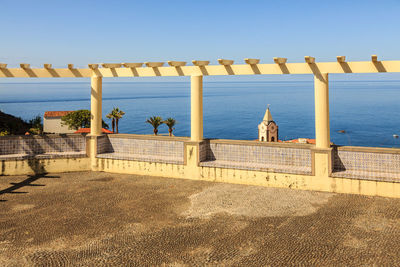 Built structure by sea against clear sky