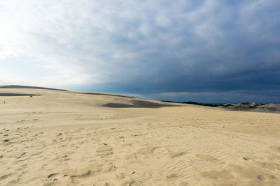 View of calm beach against cloudy sky