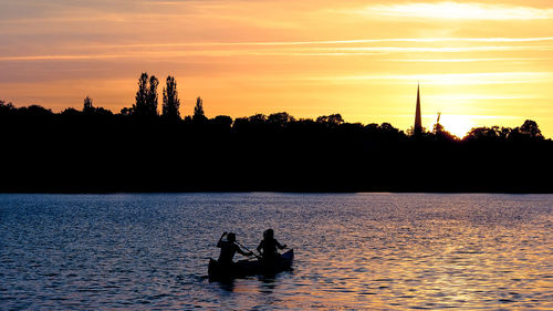 Silhouette of people kayaking on river