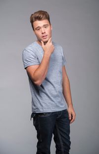 Portrait of young man standing against gray background