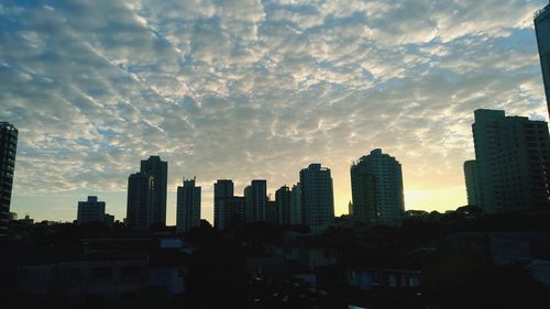 Modern buildings in city against sky during sunset