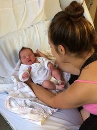 High angle view of woman holding toddler girl lying on bed