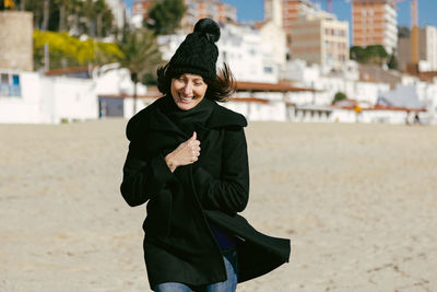 Middle-aged woman running happily along the beach on a sunny winter day