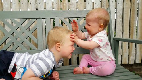 Playful siblings on wooden bench