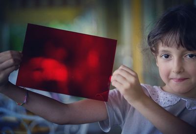 Close-up of cute girl holding red paper