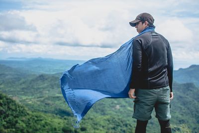 Rear view of man standing on mountain against sky