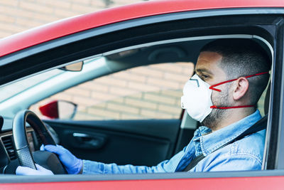 Man with mask and gloves driving a car. driving and covid-19 concept.