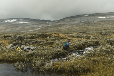 Cyclist drinking water at stream