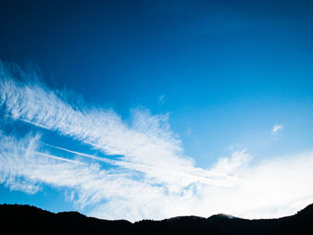 Low angle view of silhouette mountain against blue sky