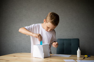 The boy cuts out details from paper. glue the parts together with glue.