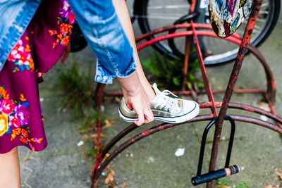 Low section of woman leaning on bicycle rack