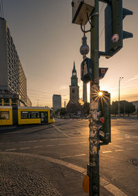 Street light by road against buildings in city at sunset