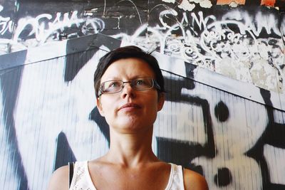 Portrait of woman against graffiti wall