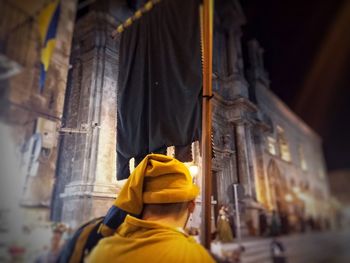 Rear view of yellow man outside temple against building