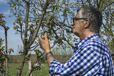 Close-up of man touching plant while standing outdoors