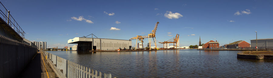 Panoramic view of harbor by river against sky