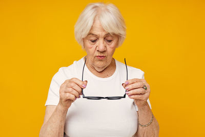 Portrait of young woman holding gift against yellow background