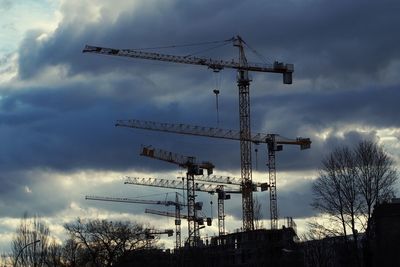 Low angle view of crane against cloudy sky