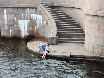 Man sitting on bridge over river