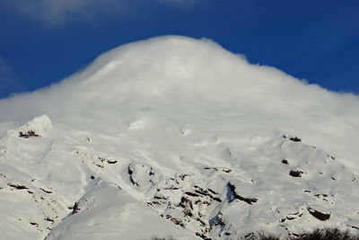 Low angle view of snowcapped mountain against blue sky