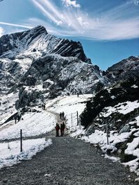 People on snowcapped mountain against sky