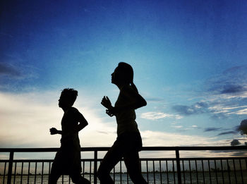 Silhouette of woman standing against blue sky