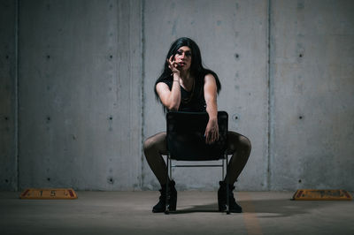 Portrait of woman sitting against wall