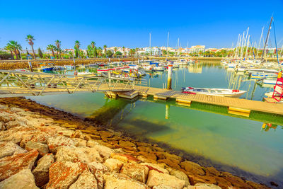 Boats moored at harbor against clear blue sky