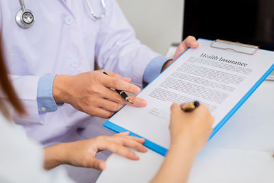 Midsection of man reading book on paper