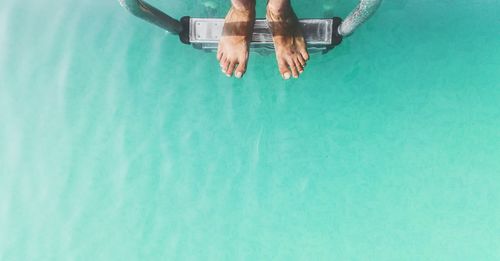 Low section of man on steps in swimming pool