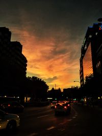 Cars on road in city against sky during sunset